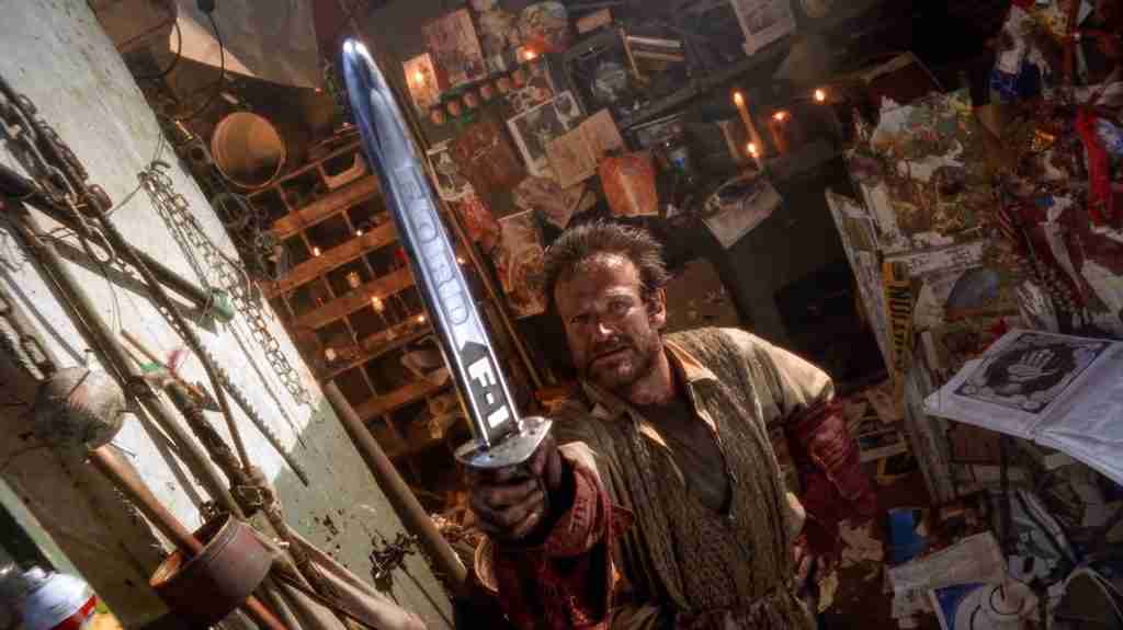 Robin Williams as Parry holding sword aloft like a knight declaring his quest to Jeff Bridges as Jack in cluttered lair from The Fisher King (1991) – key declaration scene from the Fisher King beat sheet analysis.