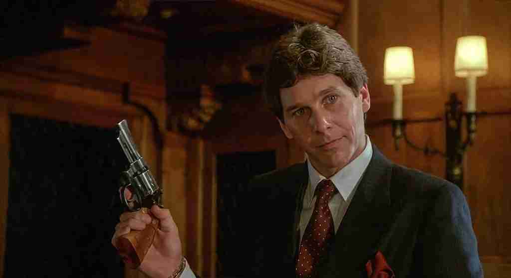 Fletch beat sheet – Tim Matheson as Alan Stanwyk holding revolver in mansion library during "I want you to murder me" proposition scene 1985 movie, Catalyst moment