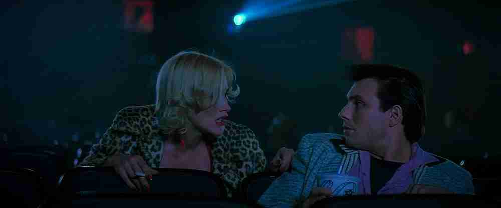 Clarence and Alabama meet in a dark movie theater; Alabama is wearing a leopard print jacket.