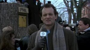 Phil Connors reporting on camera beside the "PHIL" groundhog sign in Groundhog Day