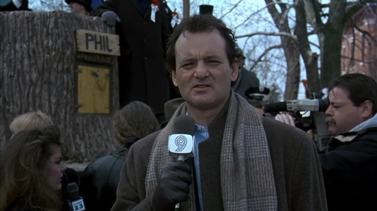 Phil Connors reporting on camera beside the "PHIL" groundhog sign in Groundhog Day