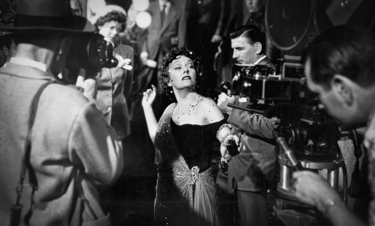 Sunset Boulevard analysis: Norma Desmond (Gloria Swanson) surrounded by newsreel cameras during the iconic final close-up scene in Billy Wilder's 1950 film noir.