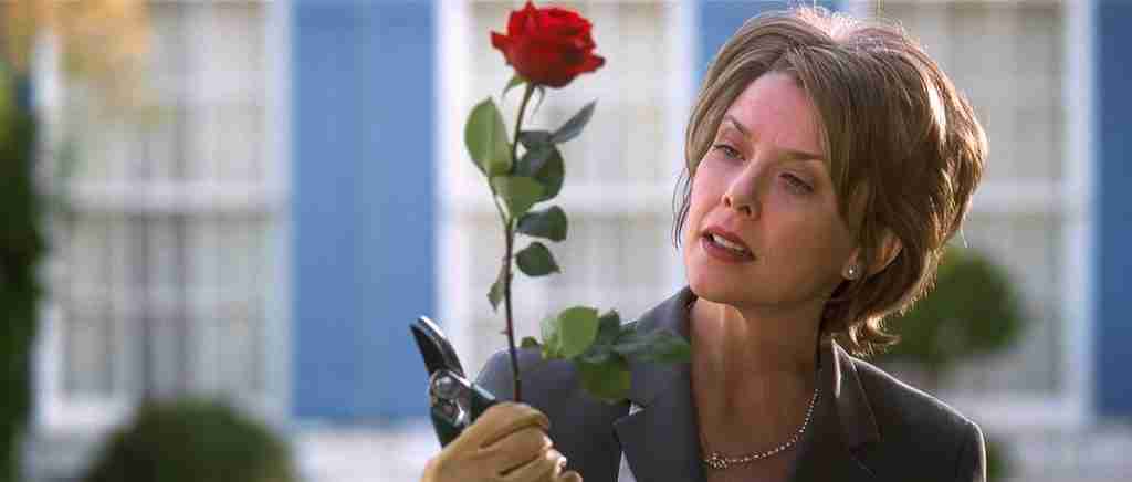 Carolyn Burnham holding a red rose and pruning shears, embodying her obsessive control in the film's setup.