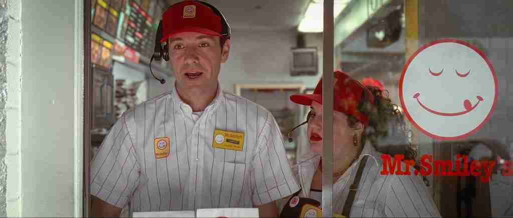 Lester Burnham smiling at the Mr. Smiley's drive-thru, embodying the freedom and defiance of the Fun and Games section on the American Beauty Beat Sheet.