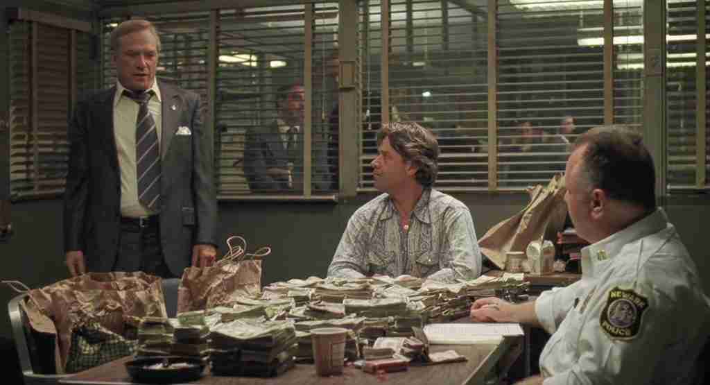 Detective Richie Roberts surrounded by stacks of illegal cash, representing his Catalyst.