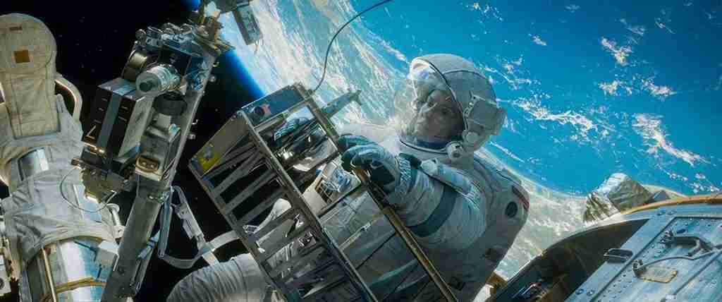 Dr. Ryan Stone in a space suit working on the Hubble Telescope against the backdrop of Earth.