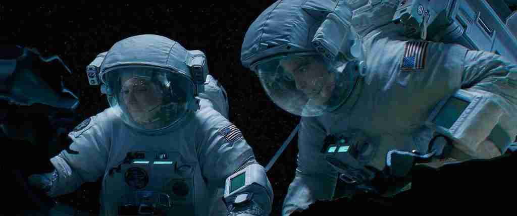 Matt Kowalski tethered to Ryan Stone, surveying the destroyed Explorer shuttle in space.