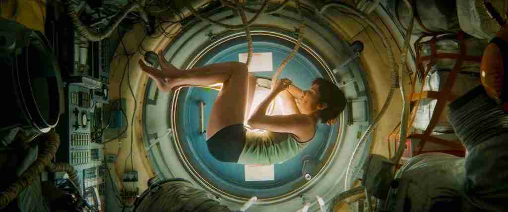 Dr. Ryan Stone, without her space suit, floating in a fetal position inside the ISS airlock.