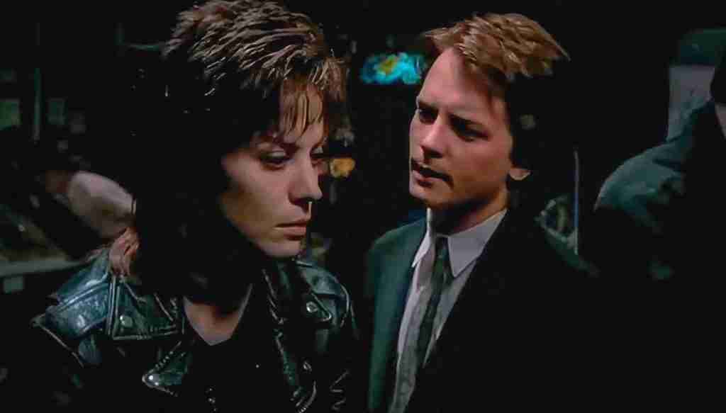 Michael J. Fox (Joe Rasnick), wearing a suit, confronts Joan Jett (Patti Rasnick) in her black leather jacket at a bar.