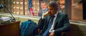 The manic Arthur Edens watches Michael Clayton through glass in the jail, symbolizing the central crisis Michael is about to encounter.