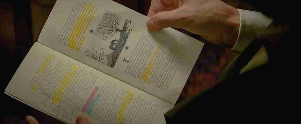 Close-up of Michael viewing Arthur Edens' highlighted Realm and Conquest book with a drawing of horses and trees.