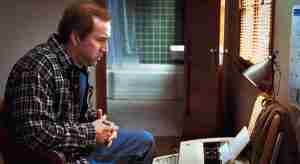 Nicolas Cage as Charlie Kaufman struggling at a typewriter, illustrating the need for screenwriting beat sheet benefits.