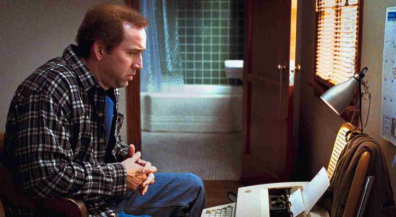 Nicolas Cage as Charlie Kaufman struggling at a typewriter, illustrating the need for screenwriting beat sheet benefits.