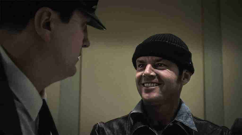 Jack Nicholson as Randall McMurphy smiling at a guard in One Flew Over the Cuckoo's Nest (1975), symbolizing the anti-establishment spirit of the AI revolution in filmmaking.