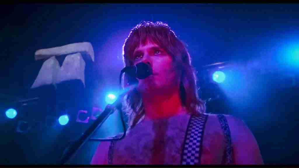 Christopher Guest as Nigel Tufnel looking upward on stage as the tiny 18-inch Stonehenge prop descends behind him, moments before dwarves dance around it, in the classic comedy scene from Rob Reiner's This Is Spinal Tap.