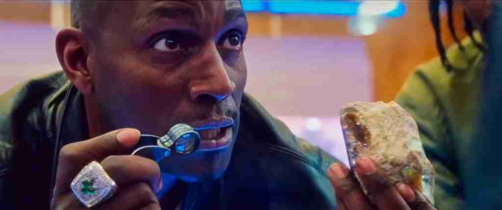 Kevin Garnett (KG) staring intensely at the black opal in Howard’s shop, used for an Uncut Gems analysis of the characters' shared obsession with luck.