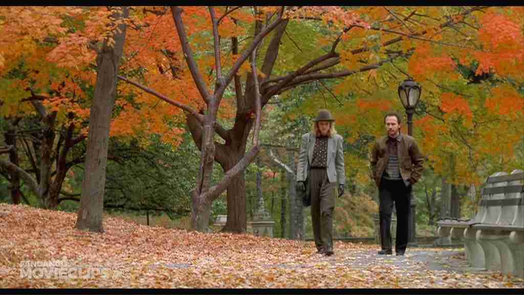 Harry and Sally walking side by side on a leaf-covered path in Central Park during autumn, with colorful orange and red trees framing the scene in When Harry Met Sally.