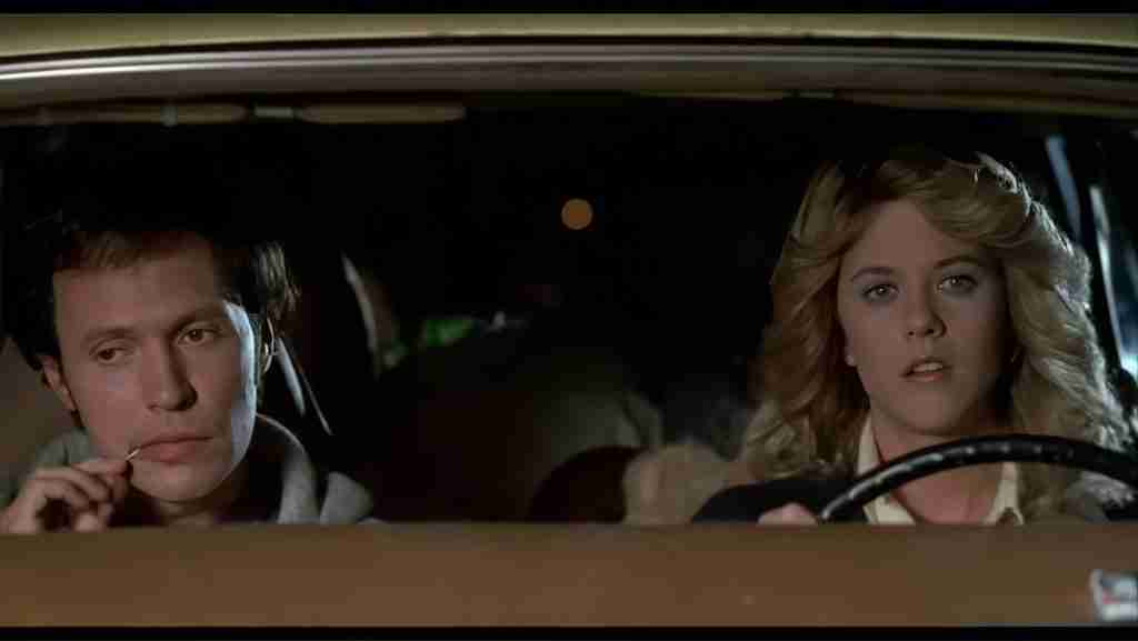 Billy Crystal (Harry) eating grapes thoughtfully while Meg Ryan (Sally) drives seriously at night, seen through the car windshield in When Harry Met Sally.