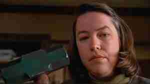 Kathy Bates as Annie Wilkes holding a sledgehammer in the iconic hobbling scene from Misery (1990) – central to this Misery analysis of psychological tension.