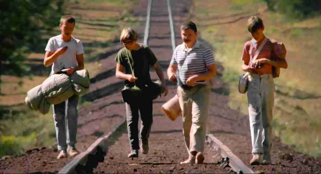 Stand By Me analysis: The four boys (Gordie Lachance, Chris Chambers, Teddy Duchamp, and Vern Tessio) walking along the train tracks, symbolizing their coming-of-age quest.