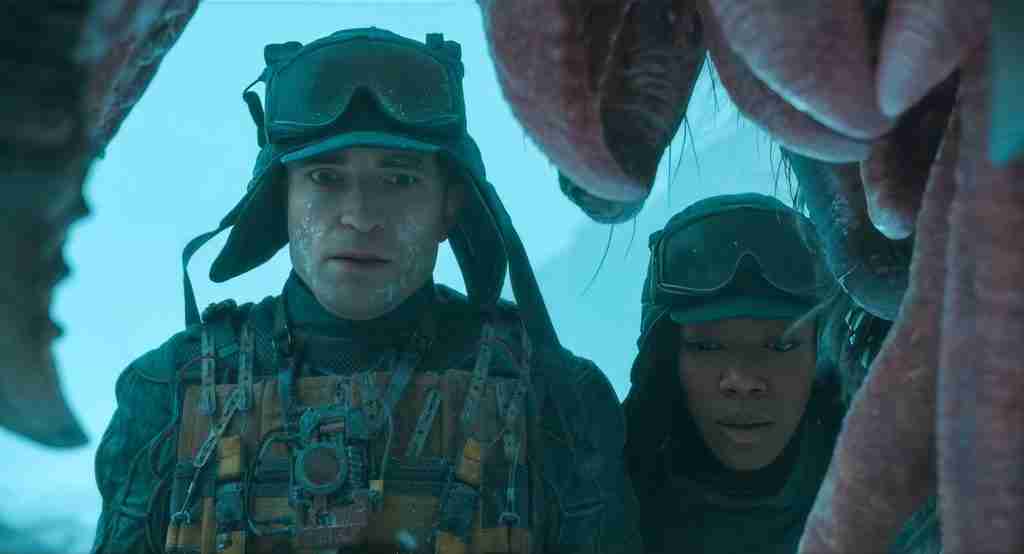 Mickey 17 analysis conclusion image: Robert Pattinson and Naomi Ackie returning baby Creeper Zoco to Mama Creeper in snowy Niflheim, symbolizing empathy, resolution, and anti-colonial themes