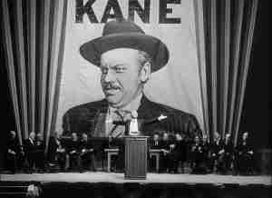Charles Foster Kane on massive campaign banner during rally in Citizen Kane, symbolizing his peak power and cult of personality