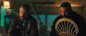 Matt Damon and Ben Affleck in tense cop conversation scene from Netflix movie The Rip 2026, dimly lit boat interior with dramatic shadows