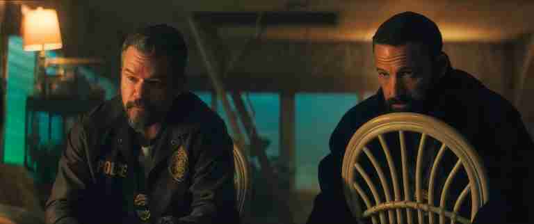Matt Damon and Ben Affleck in tense cop conversation scene from Netflix movie The Rip 2026, dimly lit boat interior with dramatic shadows