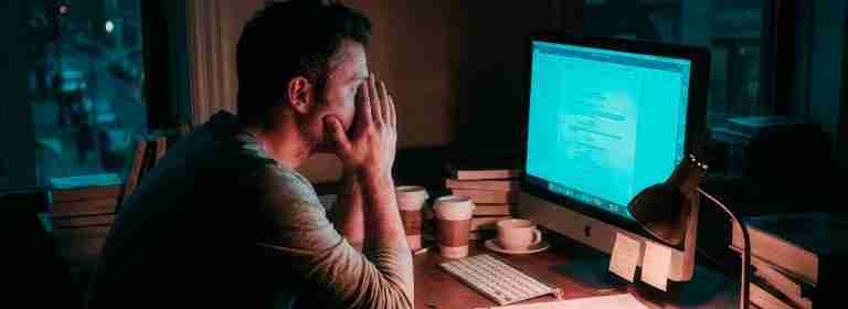 A lone screenwriter at a computer in a dimly lit room struggling to fix your Act 2 beat sheet and improve screenplay pacing.