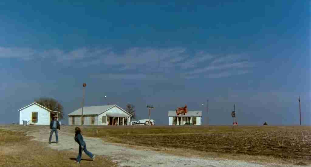 Wide shot of Robert Duvall as Mac Sledge and Sonny playing catch with a football in a desolate Texas field at the end of Tender Mercies.