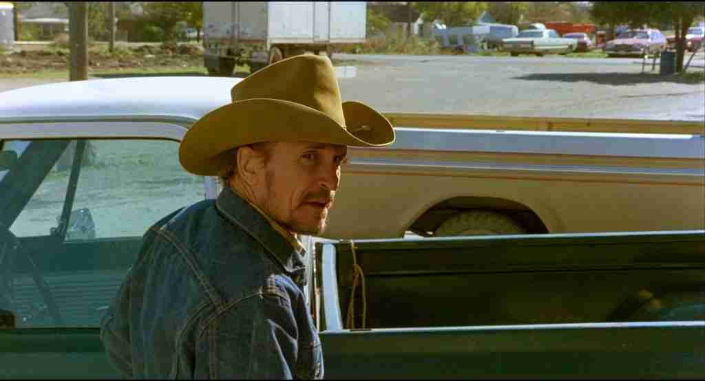 Robert Duvall as Mac Sledge in a cowboy hat looking back as he is recognized in town during a scene from Tender Mercies.