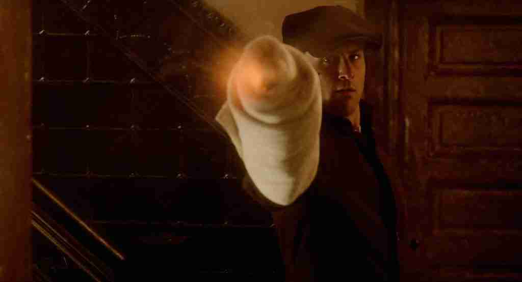 The Godfather Part II analysis: Young Vito Corleone pointing a wrapped gun at Don Fanucci in a hallway.