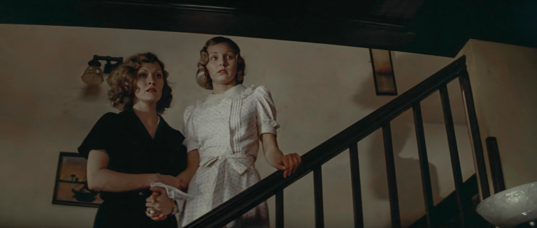 Evelyn Mulwray in black and Katherine in white standing together on a staircase in Chinatown 1974