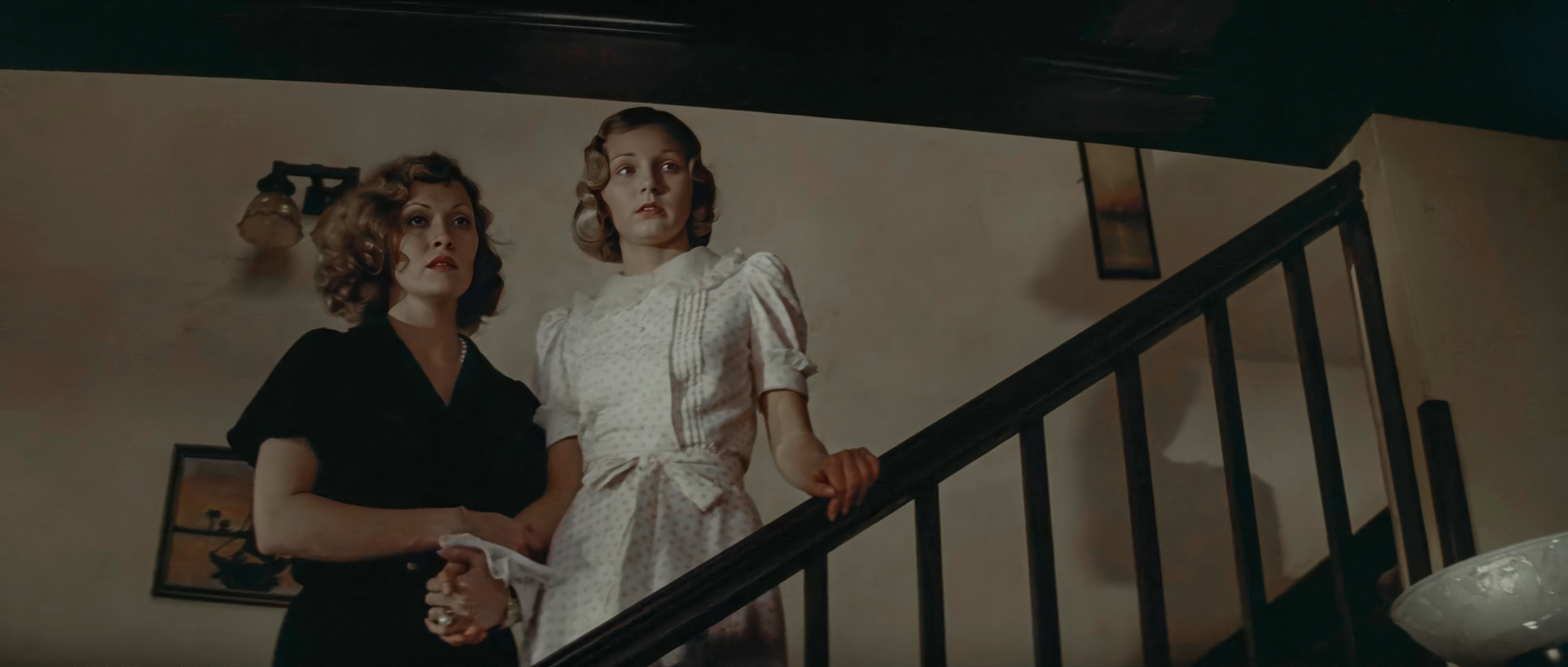 Evelyn Mulwray in black and Katherine in white standing together on a staircase in Chinatown 1974