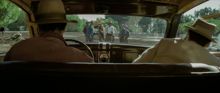 Jake Gittes's point of view through the windshield arriving at Noah Cross's Catalina ranch — Cross flanked by riders in western hats beside a horse in Chinatown 1974