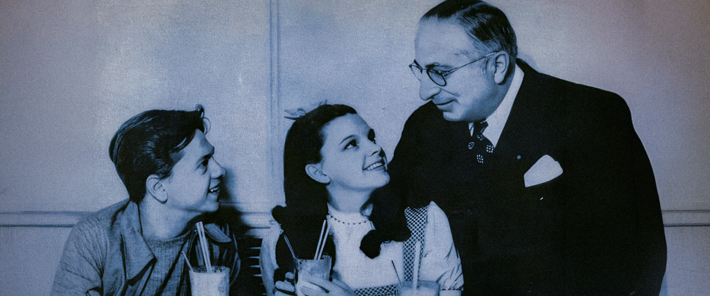 MGM publicity still of Louis B. Mayer standing between young Judy Garland and Mickey Rooney — the studio chief who founded the Academy of Motion Picture Arts and Sciences in 1927 to prevent labor organizing in Hollywood
