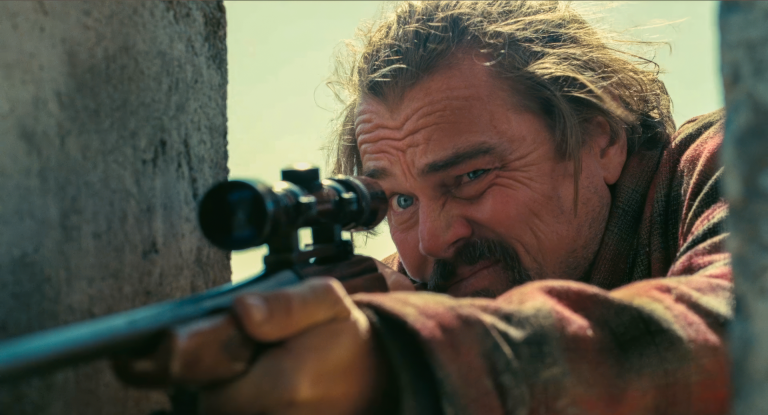 Bob Ferguson (Leonardo DiCaprio) aims through a rifle scope in One Battle After Another — the exhausted revolutionary at the center of the One Battle After Another Terminator 2 comparison