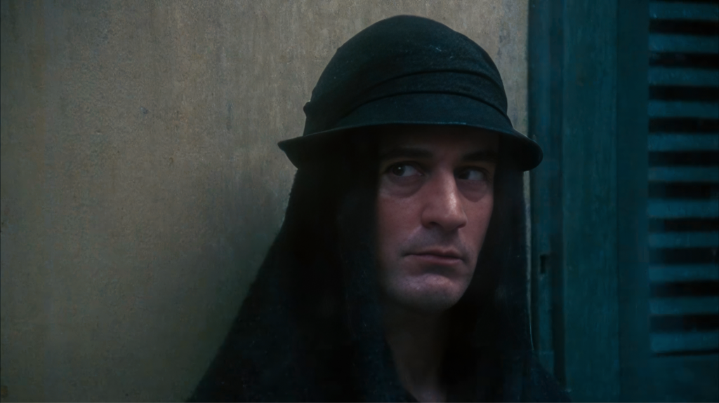 Robert De Niro's face revealed beneath the black hood of the Woman in Black cloaked figure outside Harry's hotel in Angel Heart 1987.