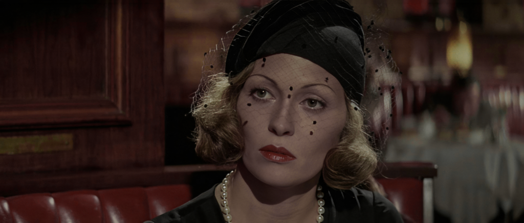 Faye Dunaway as Evelyn Mulwray in Chinatown, wearing a black veiled hat in the Brown Derby restaurant scene