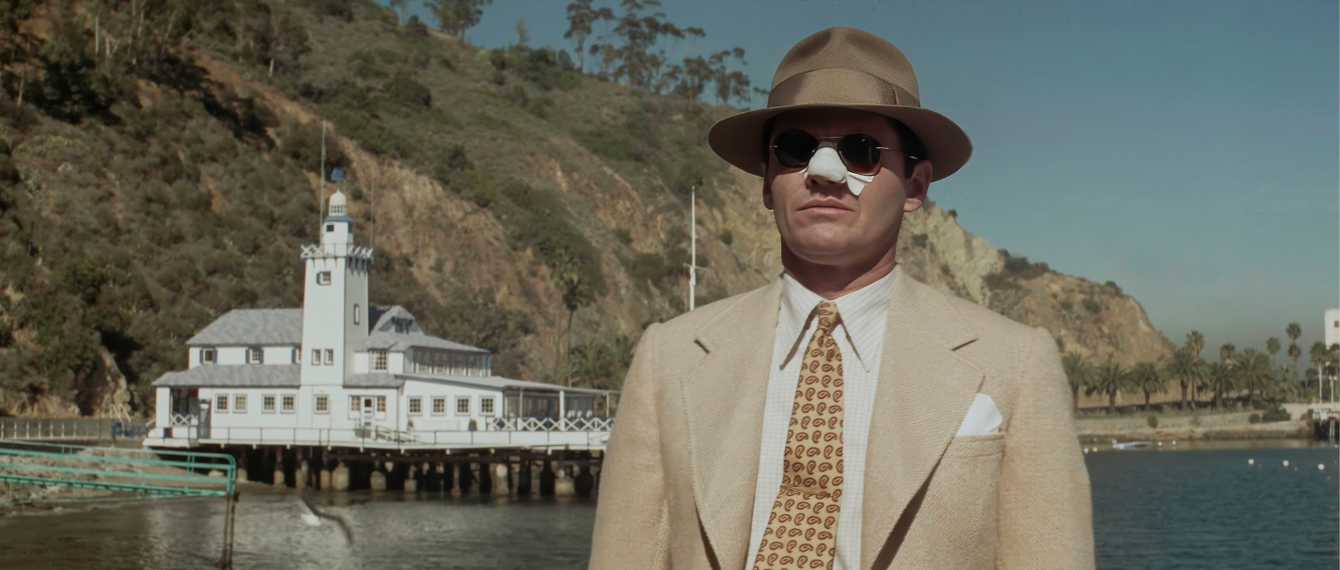 Jake Gittes in tan suit and bandaged nose arriving at the Albacore Club on Catalina Island, a scene from the film adapted from the Robert Towne Chinatown screenplay