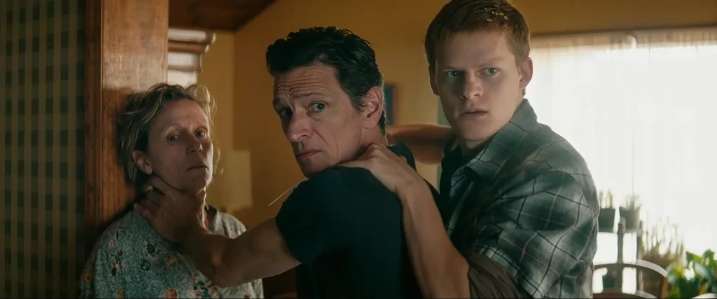 Robbie holds a knife to his father Charlie's throat as Charlie pins Mildred against the wall in Three Billboards Outside Ebbing, Missouri