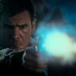 Deckard in the rain, arm extended, firing his pistol straight at the camera, muzzle flash blooming white